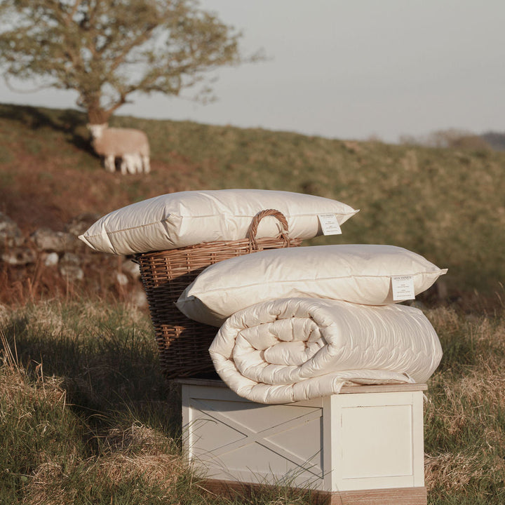 Stack of pillows and a quilt on a wooden box with a pastoral background